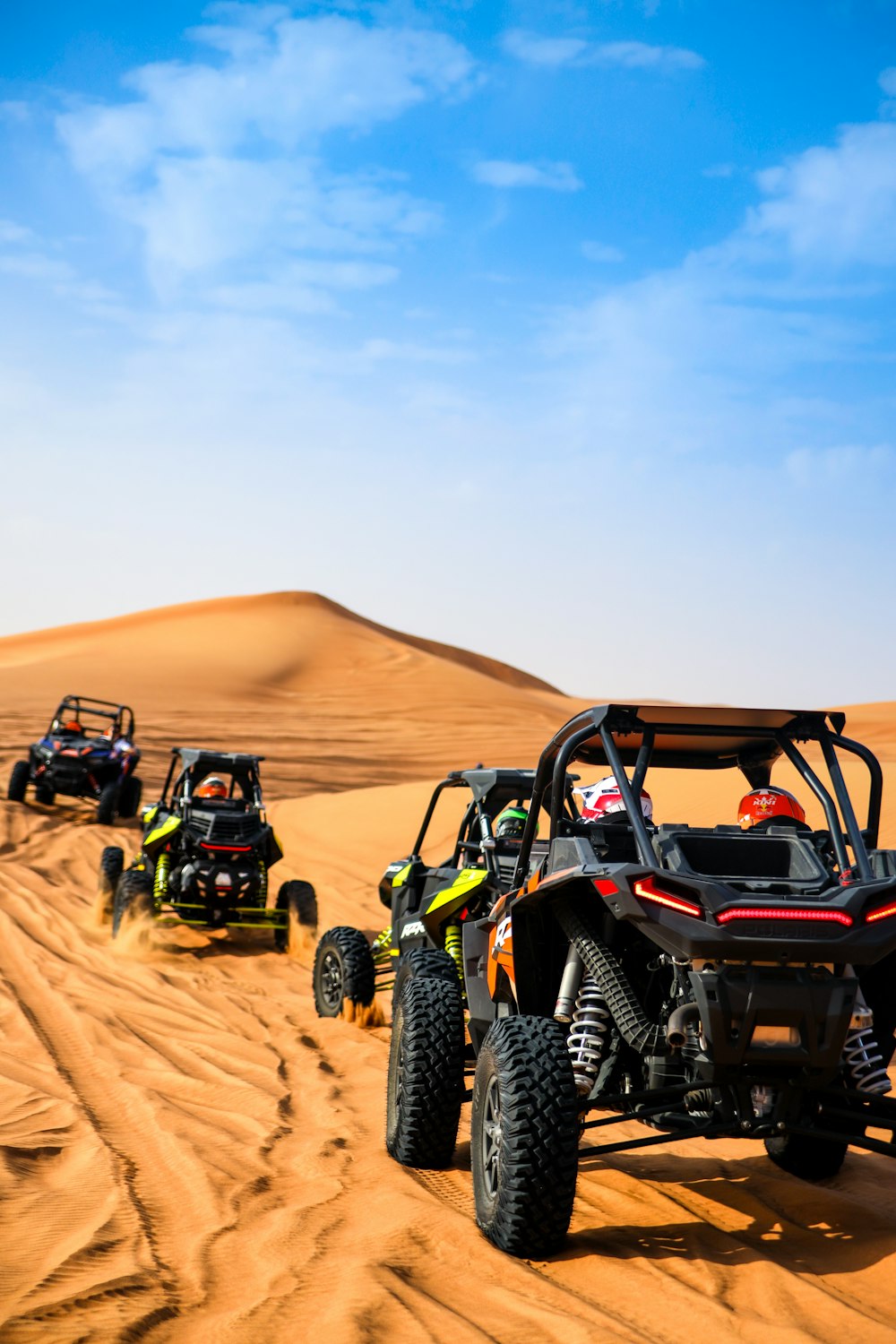 a group of four buggies driving through the desert
