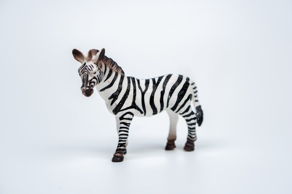 a toy zebra standing on a white surface