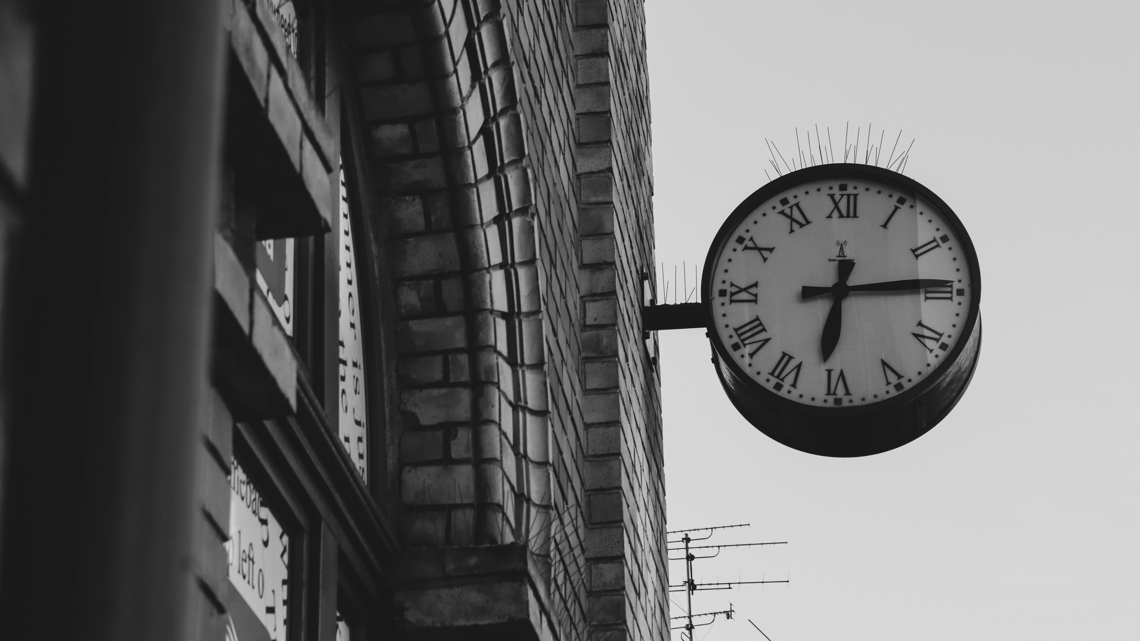 Ein Schwarz-Weiß-Foto einer Uhr an der Seite eines Gebäudes