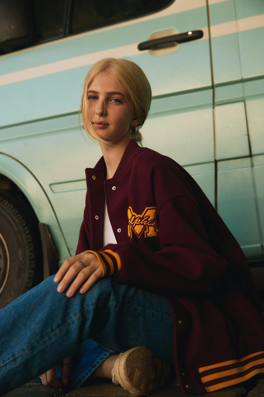 a woman sitting on the ground next to a car