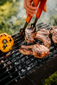 a person grilling steaks and vegetables on a grill