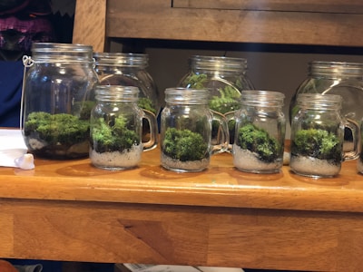 A collection of slime jars with glitter, beads, and foam toppings arranged on a wooden table.