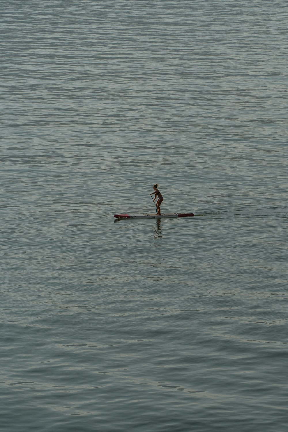 eine Person, die mit einem Paddelboot auf einem großen Gewässer fährt