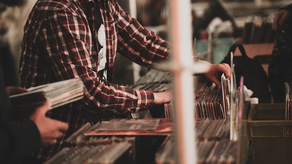 a man in a plaid shirt is working on a piece of wood