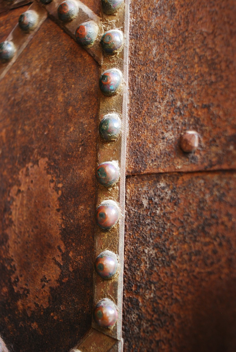 a rusted metal surface with rivets and rivet holes