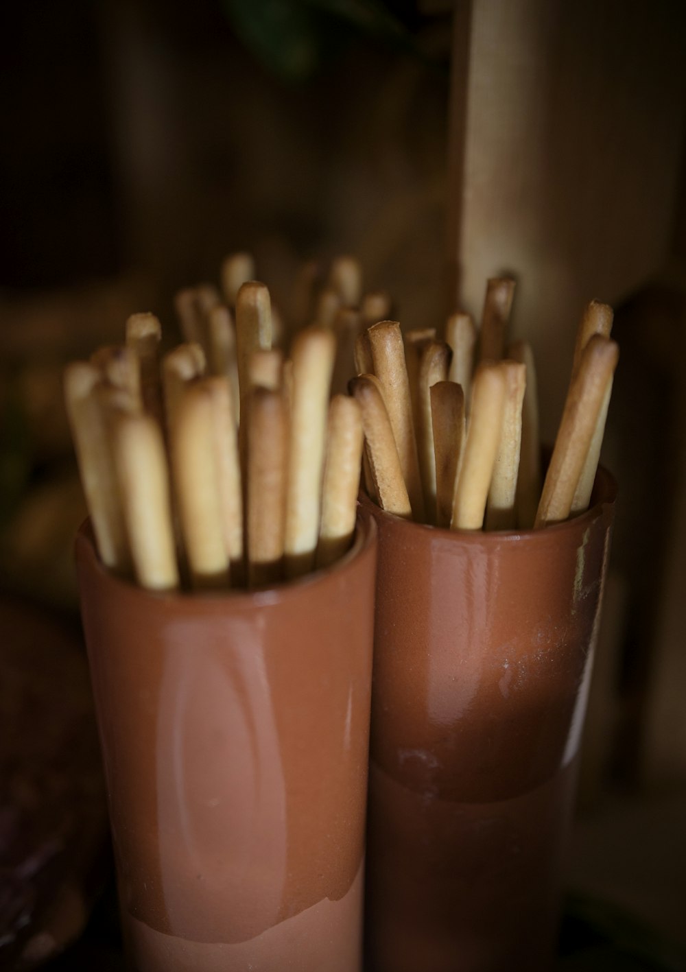 a couple of brown cups filled with sticks