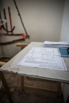 Close-up of hands reviewing technical documents and blueprints on a wooden table.