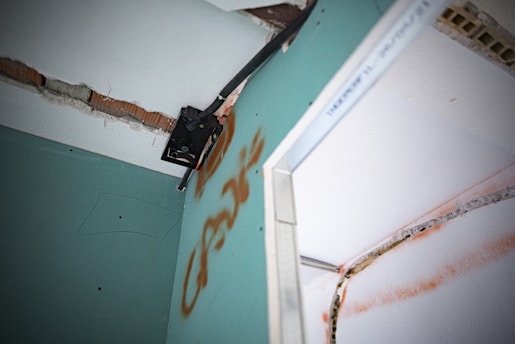 A close-up of a home inspector examining a wall for defects with a clipboard in hand.