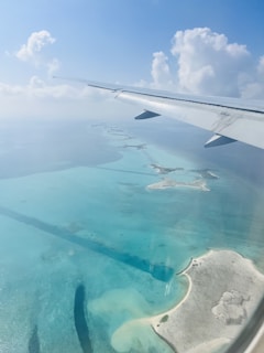 A scenic shot of a plane flying over Cancun's turquoise beaches.