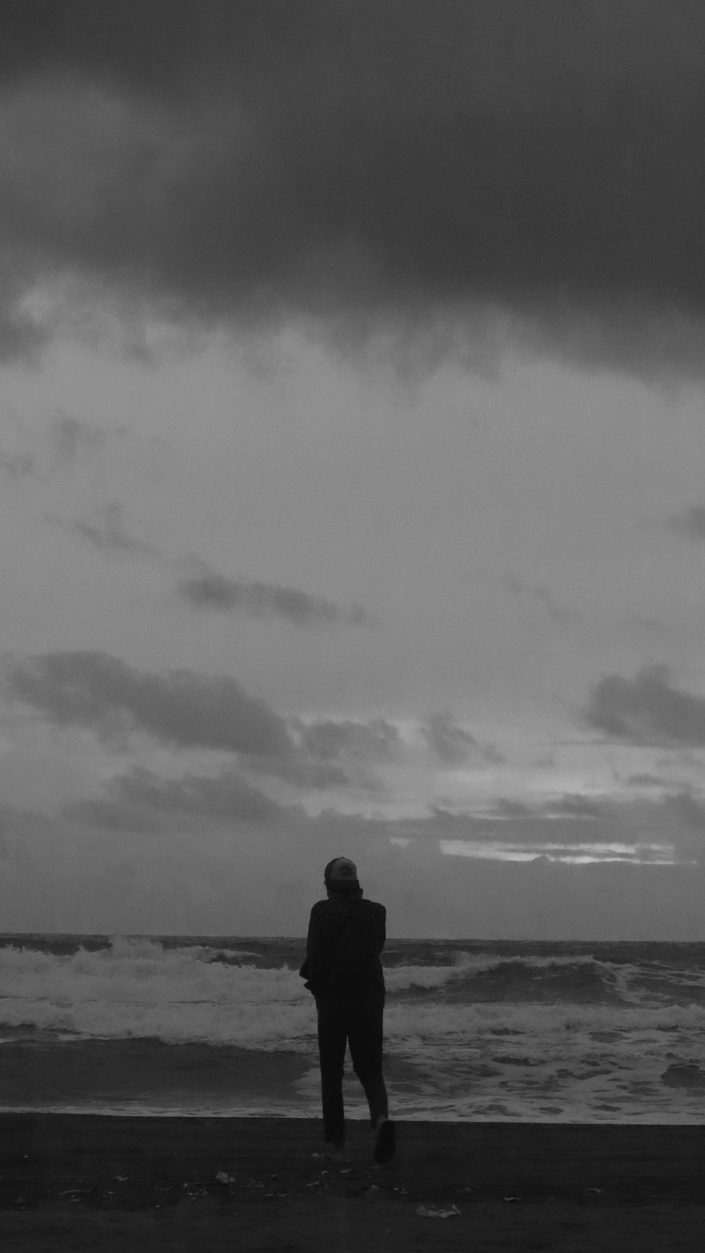 Un uomo in piedi sulla cima di una spiaggia vicino all'oceano