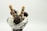 A glass dessert dish filled with vanilla ice cream topped with chocolate syrup, chocolate-covered candies, and two rolled wafer sticks. The presentation is elegant and delicious.