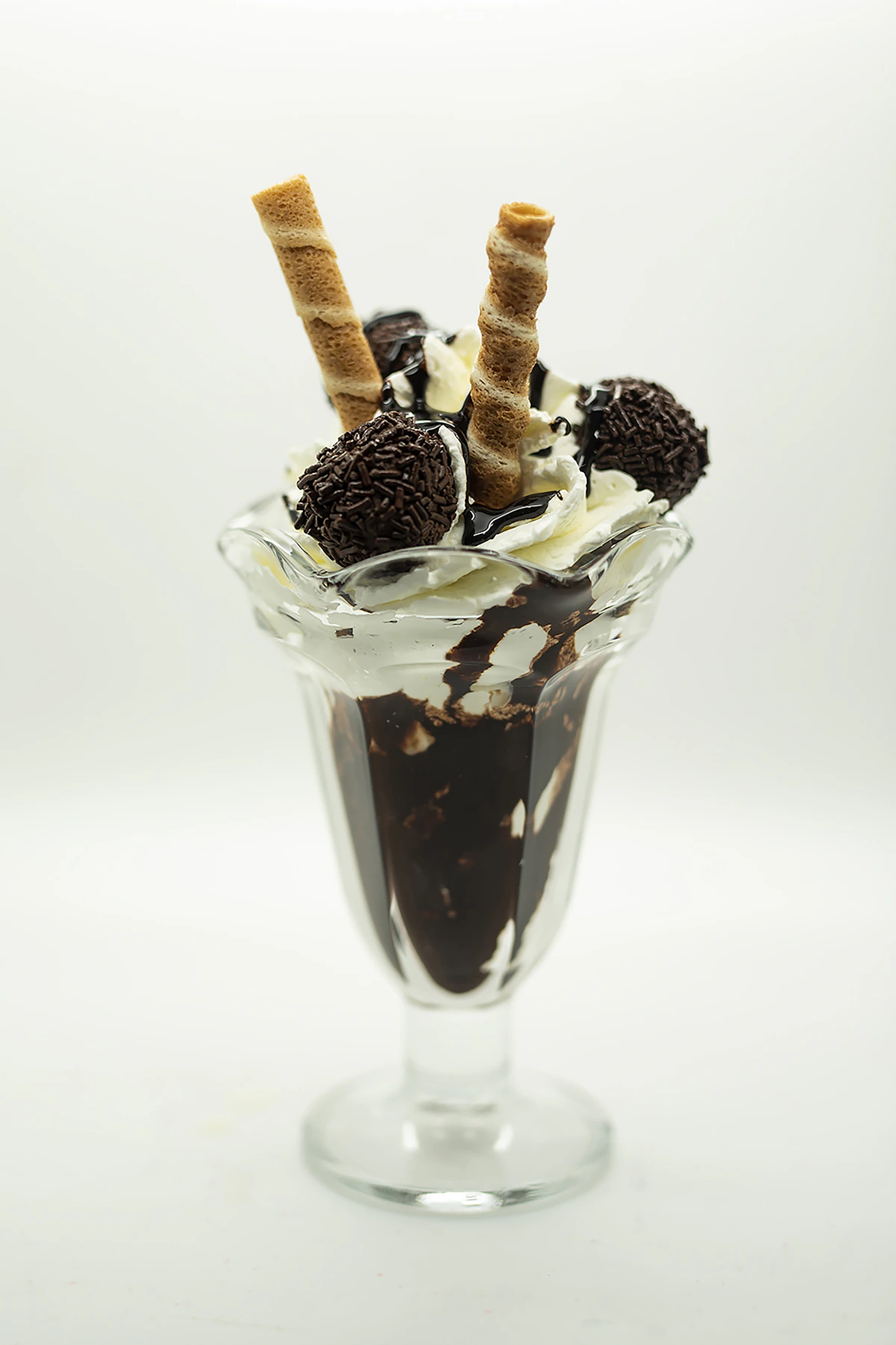 Chocolate ice cream sundae with whipped cream, cookies, and wafer rolls