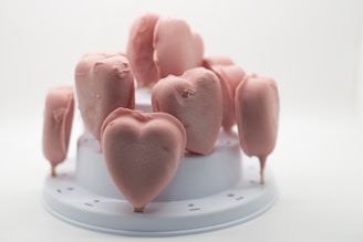 An arrangement of pink, heart-shaped frozen treats placed on a white tiered stand.