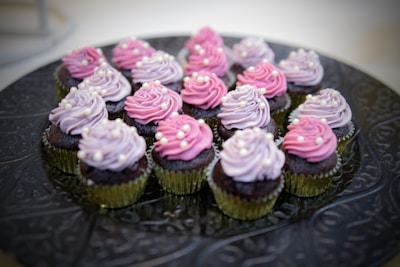 A colorful assortment of cupcakes filled with creamy vanilla and chocolate centers, arranged on a rustic wooden tray.