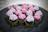 A box of assorted cupcakes in soft pastel colors, topped with intricate frosting swirls and edible pearls.