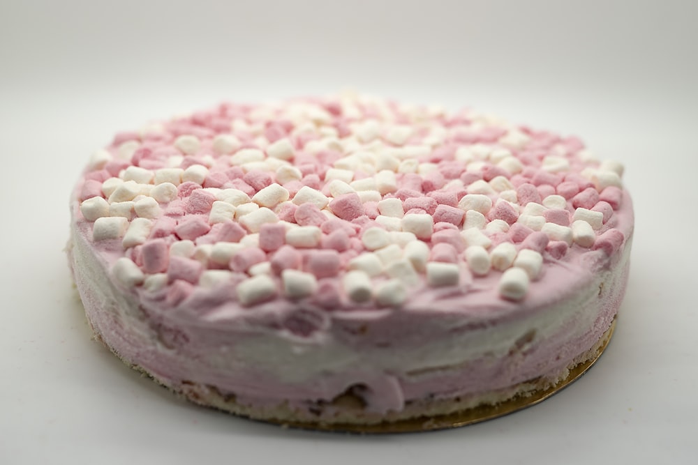 a cake with pink and white frosting and sprinkles