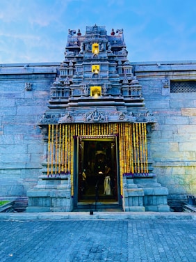 A peaceful view of the temple entrance adorned with marigold garlands during morning prayers.