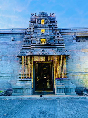 Ancient temple entrance framed by vibrant marigold garlands and soft morning light.