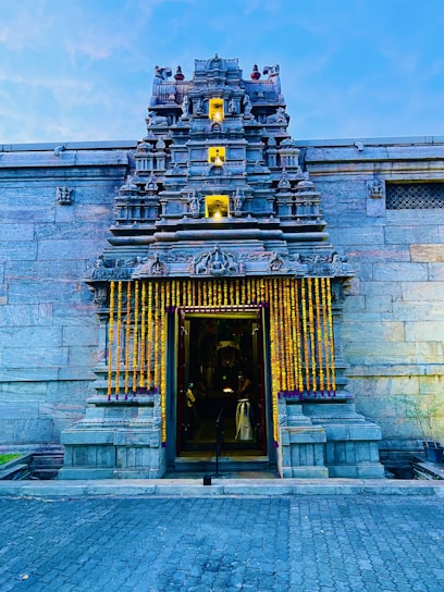 A peaceful view of the temple entrance adorned with marigold garlands during morning prayers.