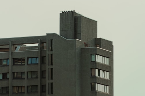 Minimalist architectural exterior with dark gray tones and soft pastel brown accents.