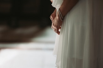 A softly lit photo of a flowing linen dress in warm beige tones, styled with delicate gold jewelry.