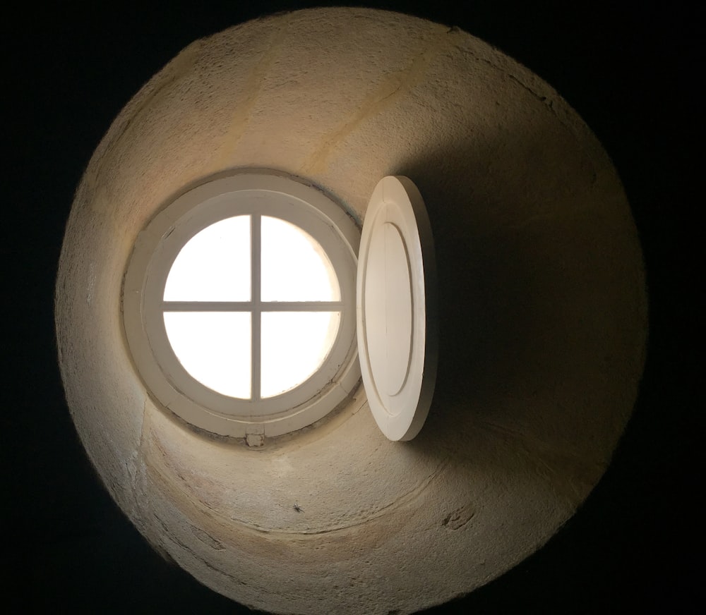 a round window in a stone wall with light coming through it