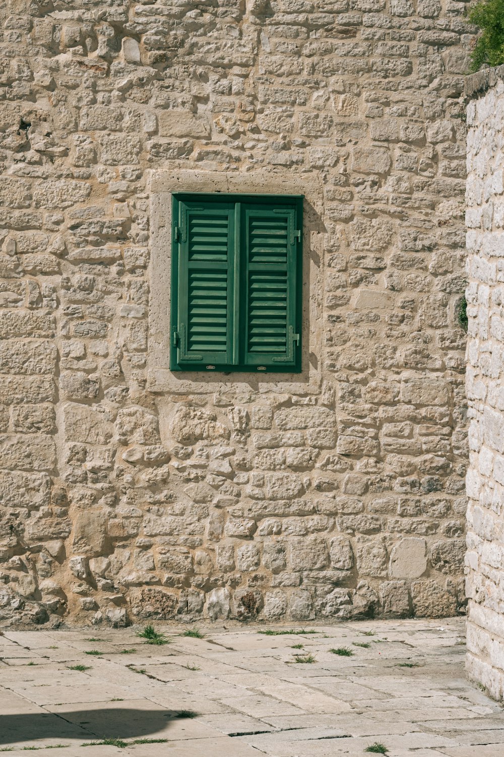 a stone building with a green window and green shutters