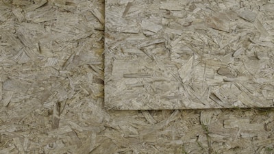 An image of overlapping sheets of oriented strand board (OSB), which consists of compressed wood strands arranged in varied directions.
