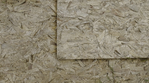 An image of overlapping sheets of oriented strand board (OSB), which consists of compressed wood strands arranged in varied directions.