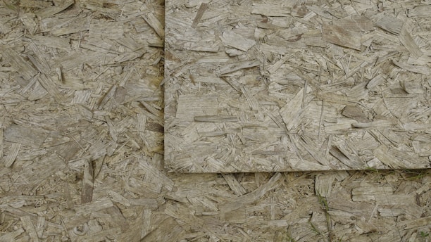 An image of overlapping sheets of oriented strand board (OSB), which consists of compressed wood strands arranged in varied directions.