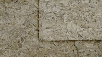 An image of overlapping sheets of oriented strand board (OSB), which consists of compressed wood strands arranged in varied directions.