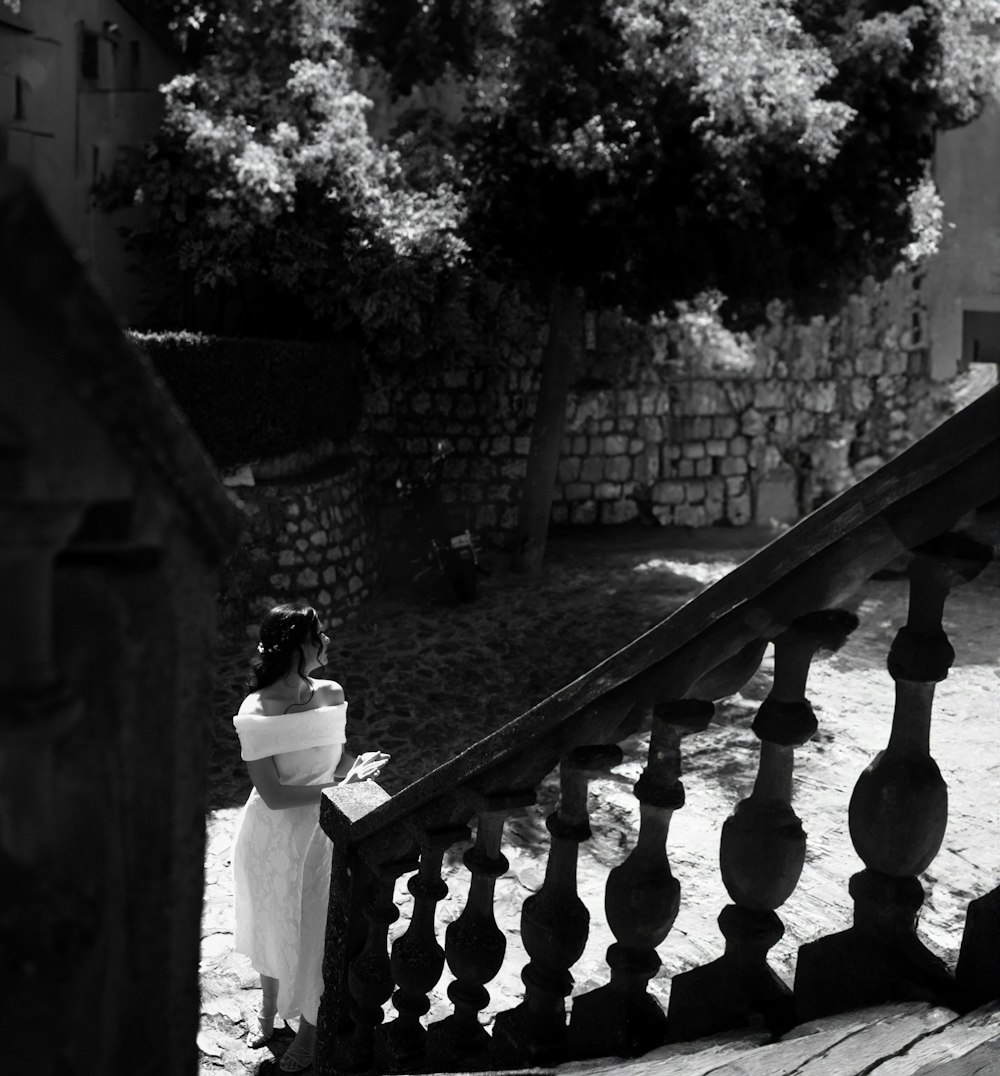 a woman in a white dress standing on a stair case