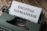 a close up of a typewriter with a paper that reads digital nomadism