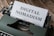 A vintage typewriter with a sheet of paper in its platen. The paper has the words 'DIGITAL NOMADISM' typed in bold, clear letters. The typewriter is placed on a rustic wooden surface, conveying a blend of nostalgia and modernity.