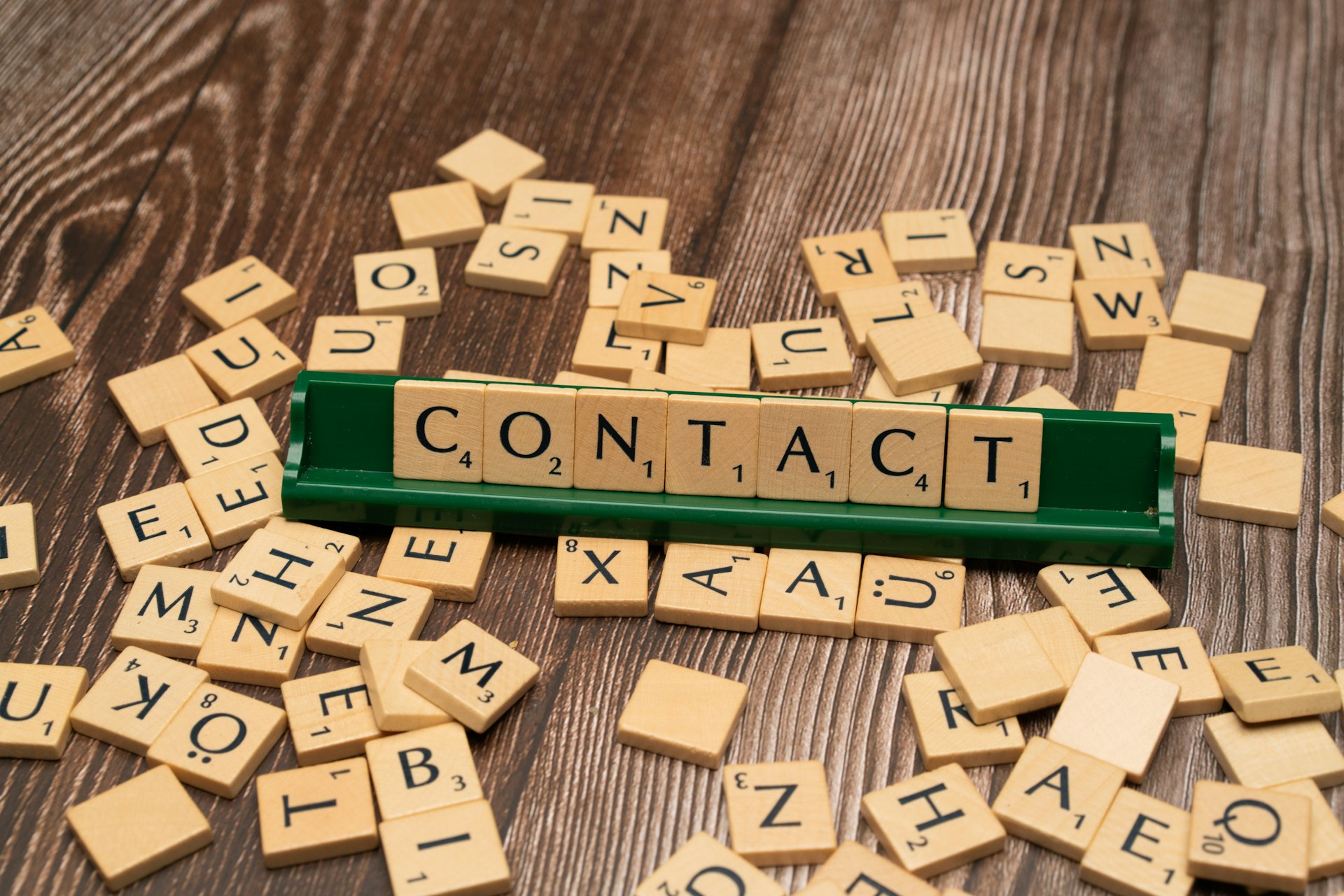 scrabble tiles spelling contact on a wooden table