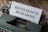 An old-fashioned typewriter holds a sheet of paper with the words 'RESILIENCE BUILDING' typed on it. The machine sits on a rustic wooden table, and the typewriter features a sleek, dark green exterior with metallic components.