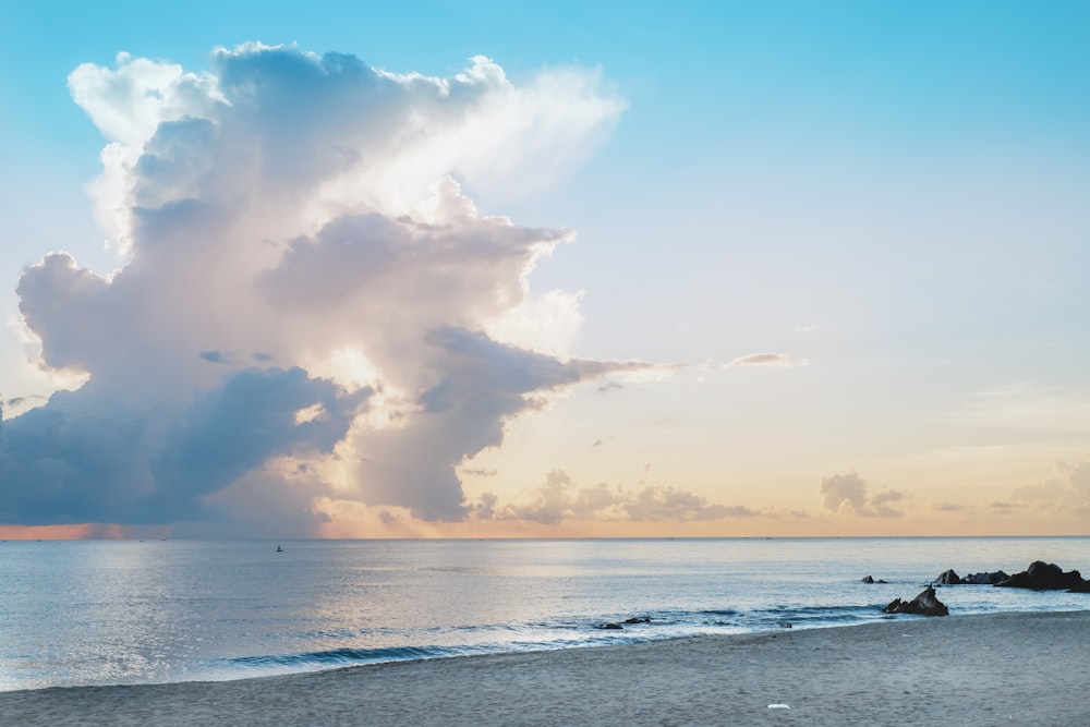 Eine große Wolke steht am Himmel über einem Strand