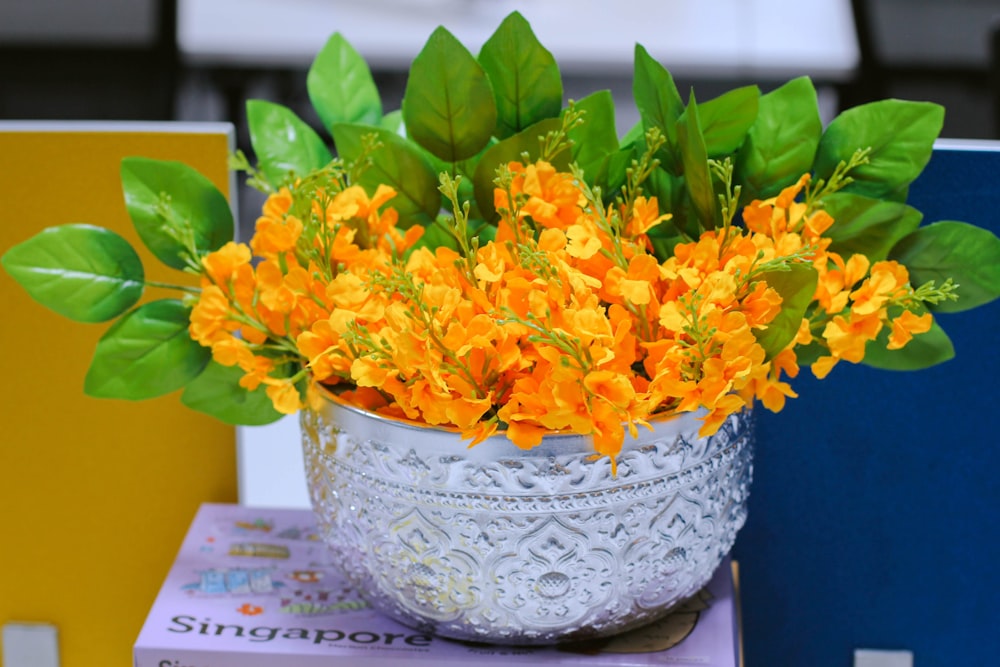 a white vase filled with yellow flowers on top of a stack of books