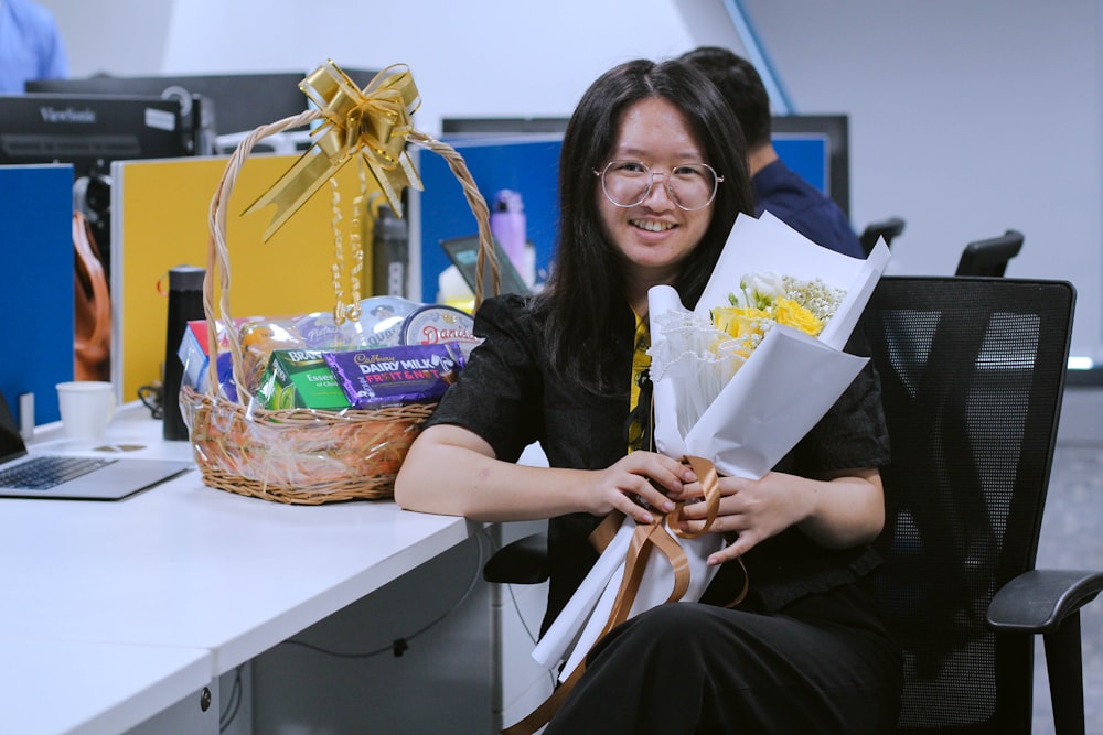 a woman sitting at a desk with a basket of flowers