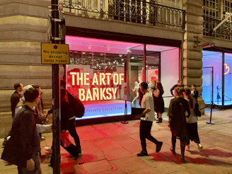 Visitors admiring a large Banksy mural in an urban outdoor gallery setting.