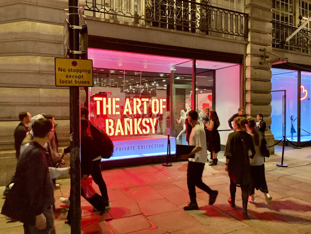 Visitors admiring a large Banksy mural in an urban outdoor gallery setting.
