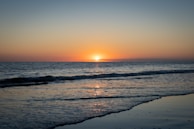 A serene beach scene with gentle waves and a sunset.