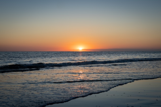 A serene beach scene with gentle waves and a sunset sky.