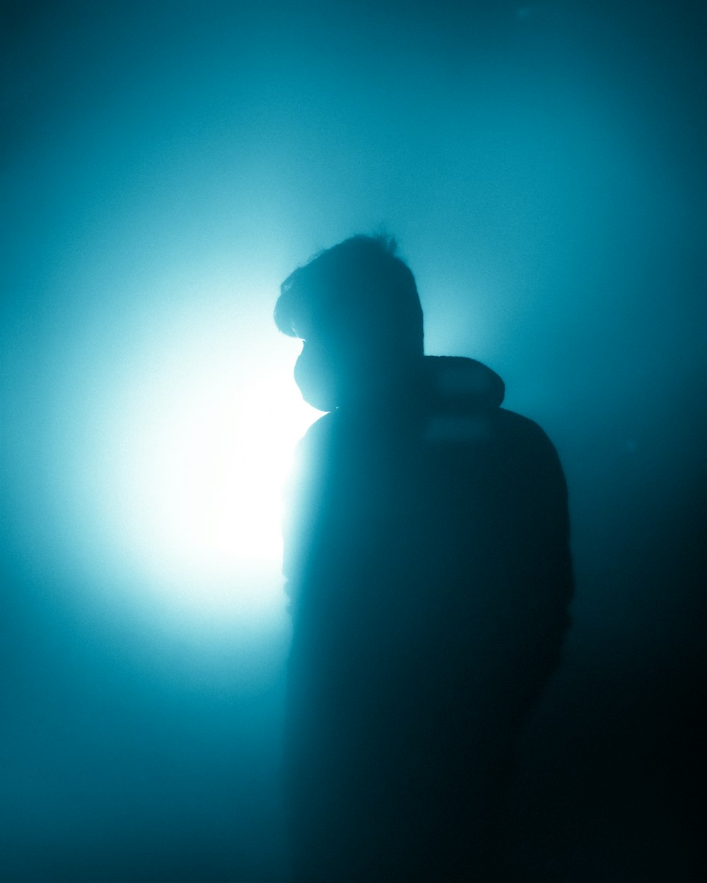 a man standing in the dark with a hat on