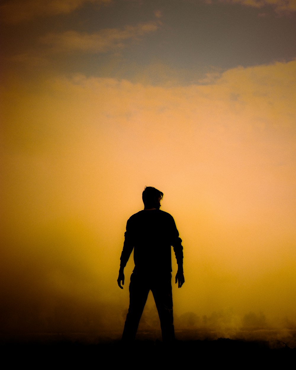 a silhouette of a man standing in front of a sunset