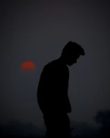 A silhouette of a lone figure standing on a cliff against a blood-red moon.