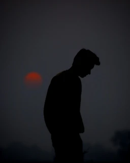 A silhouette of a lone figure standing on a cliff under a blood-red moon.