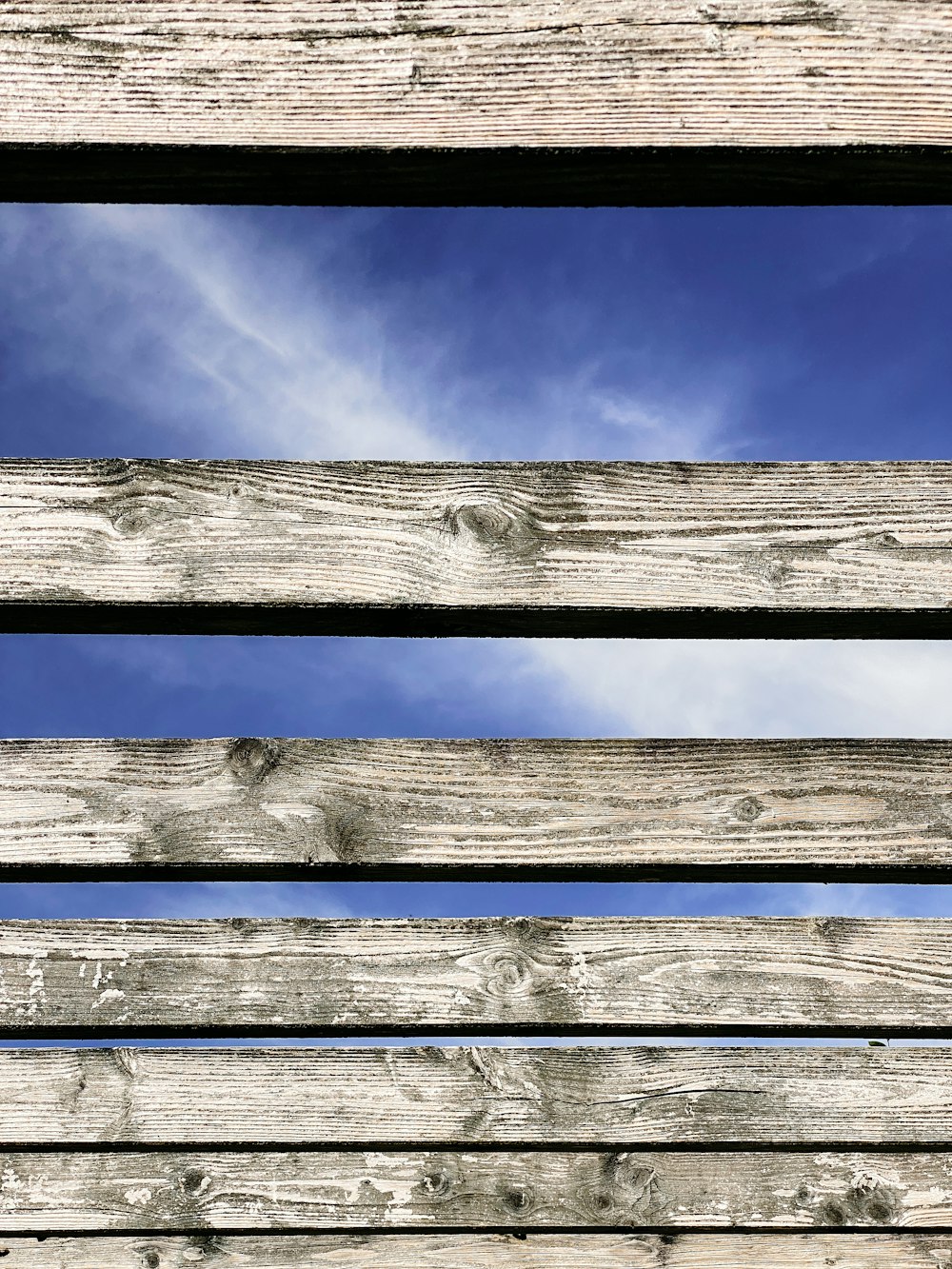 a close up of a wooden bench with sky in the background