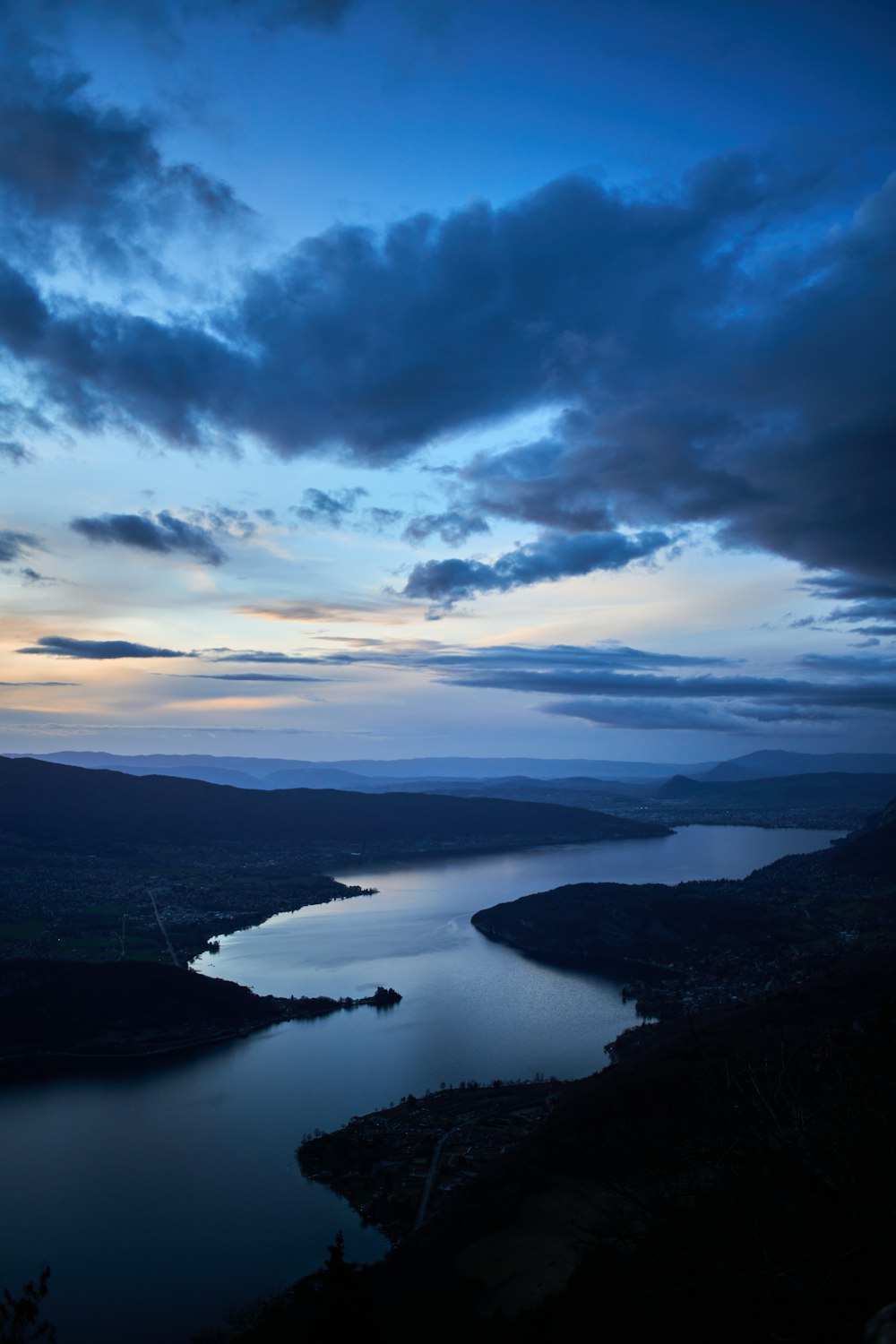 a body of water surrounded by mountains under a cloudy sky