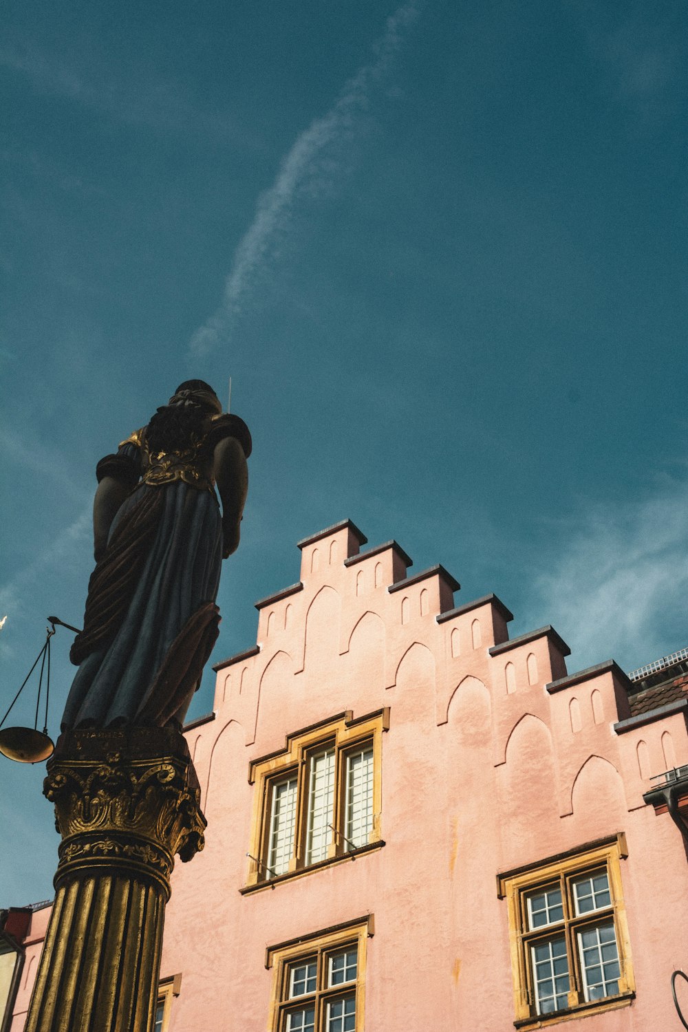 Una estatua de una dama sosteniendo una balanza frente a un edificio
